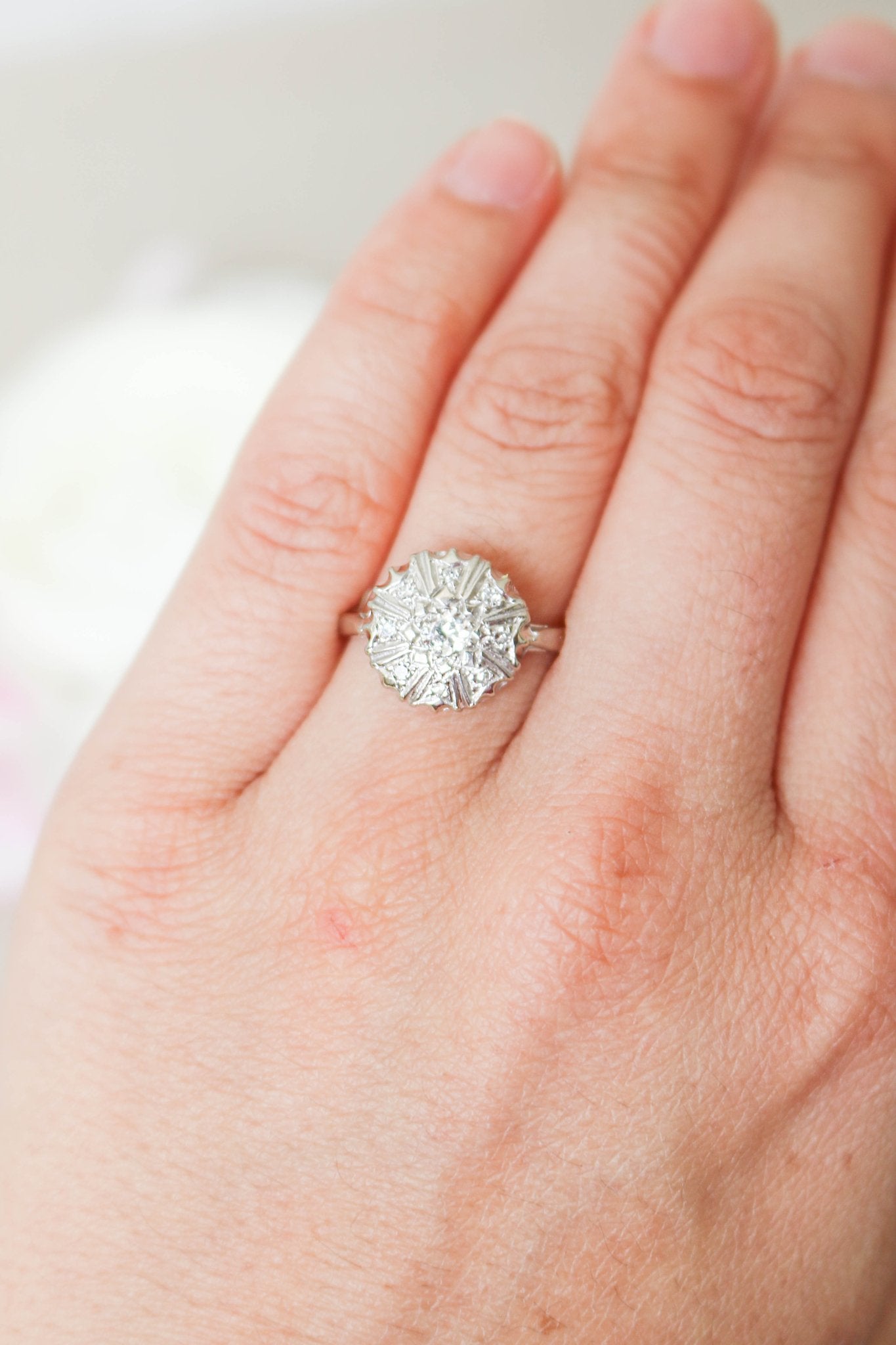 A 14k White Gold Wide-topped Diamond Vintage Engagement Ring on a ring finger. 