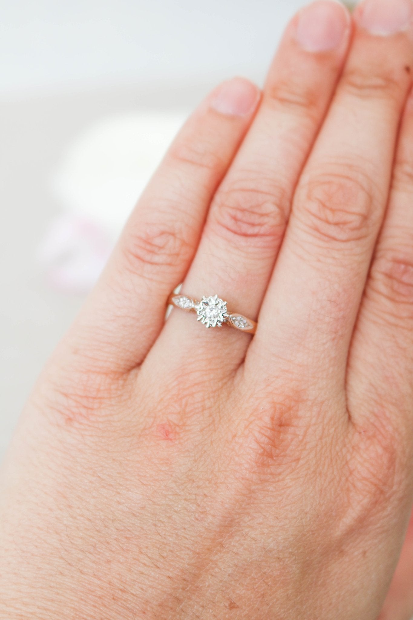 A Serena Diamond Vintage Engagement Ring in 9ct Yellow and White Gold on a ring finger. 