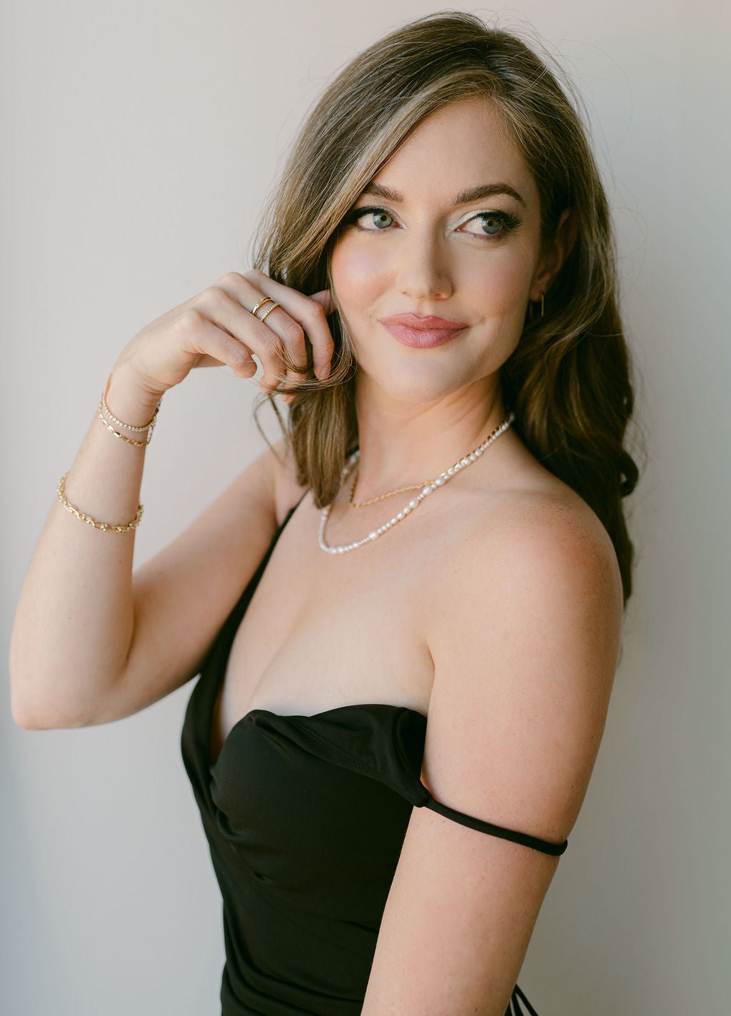 Woman in black dress with gold-filled bracelet stack and organic freshwater pearl string necklace. Organic pearl jewelry. Pearl jewelry Canada.
