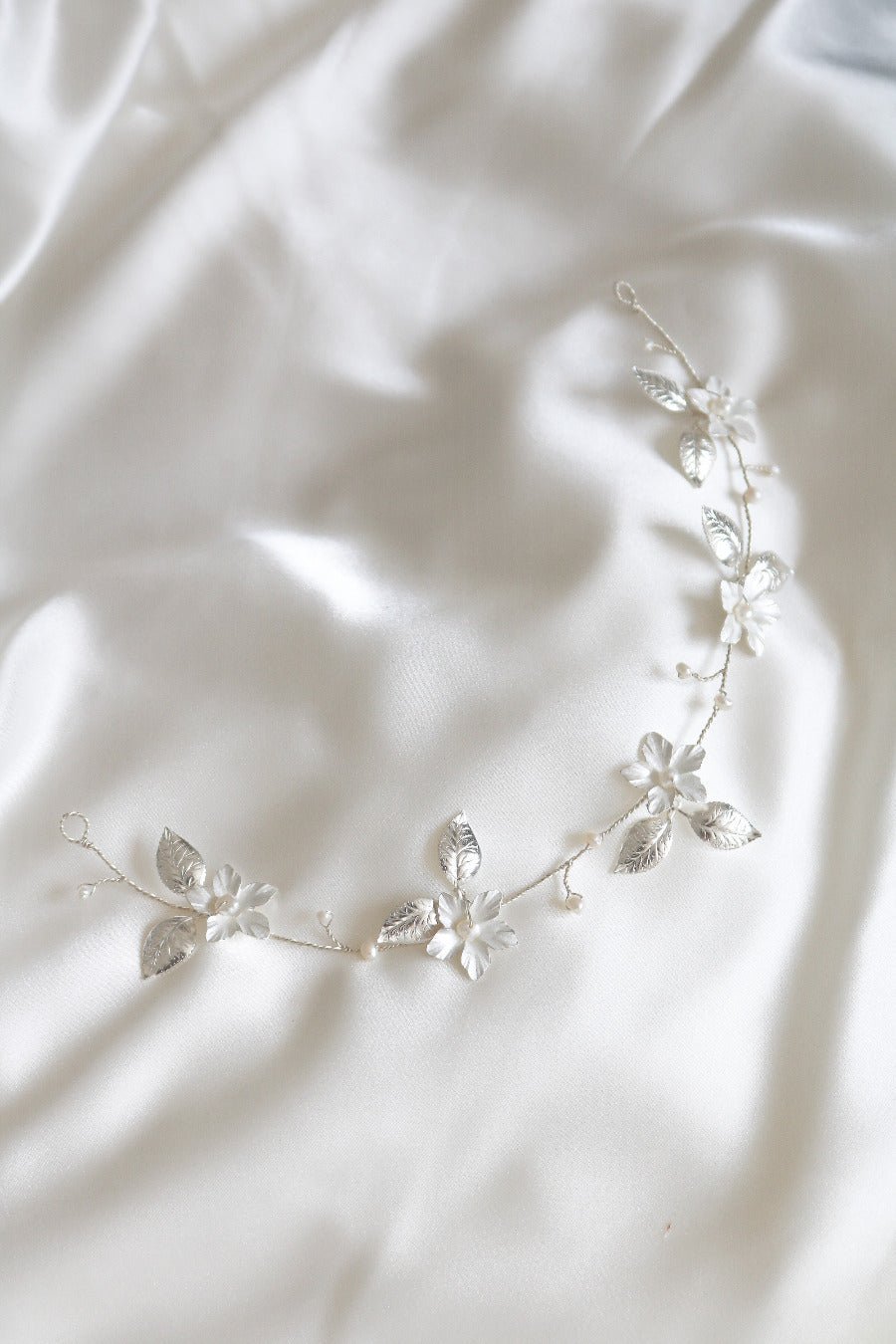 The Spring Bridal Hairvine with Fresh Water Pearls in Silver on a white satin sheet. 