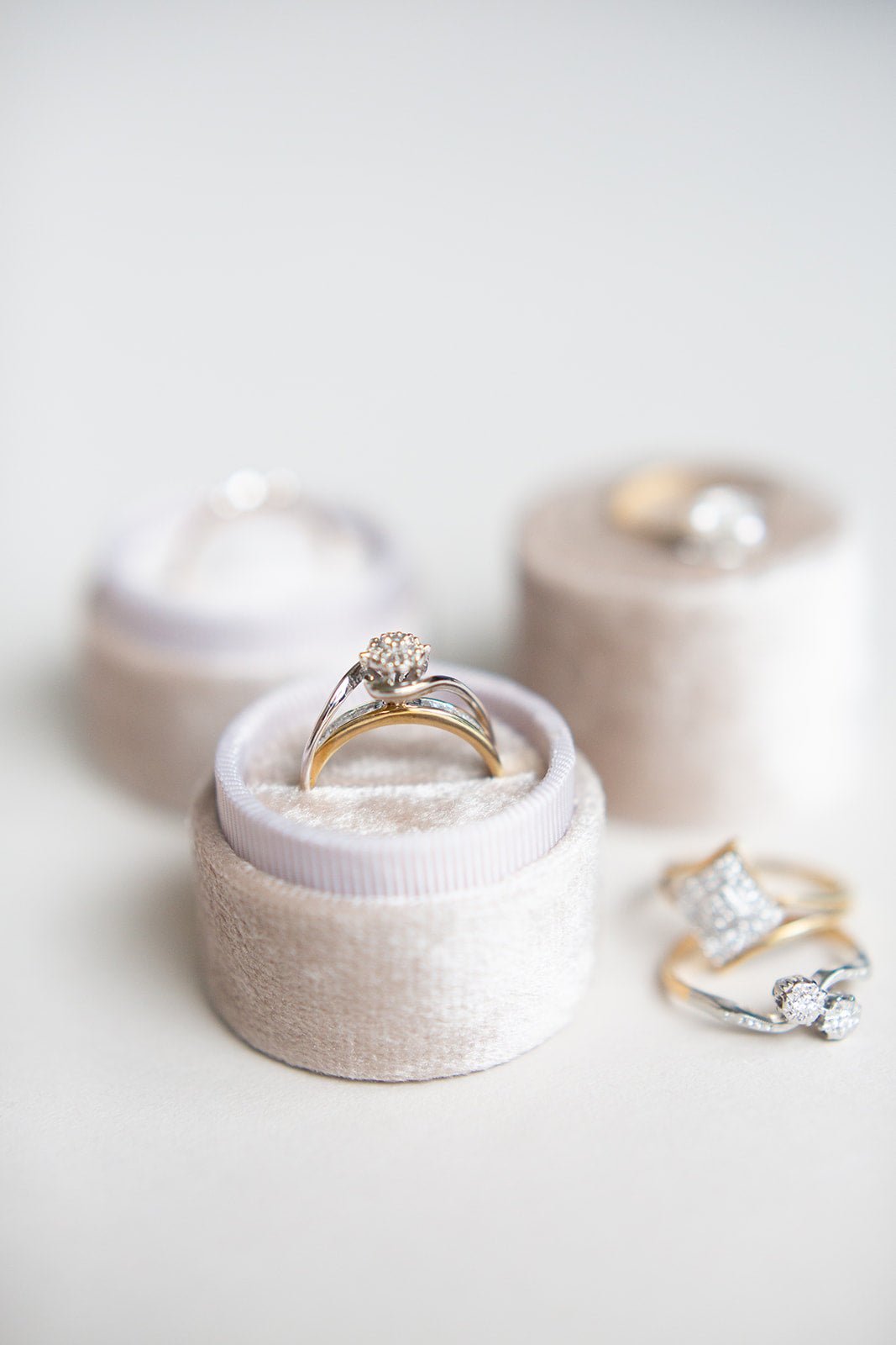 Front view of the Swan Gold and Diamond Vintage Engagement Rings in a round ring box with blurred rings around it. 