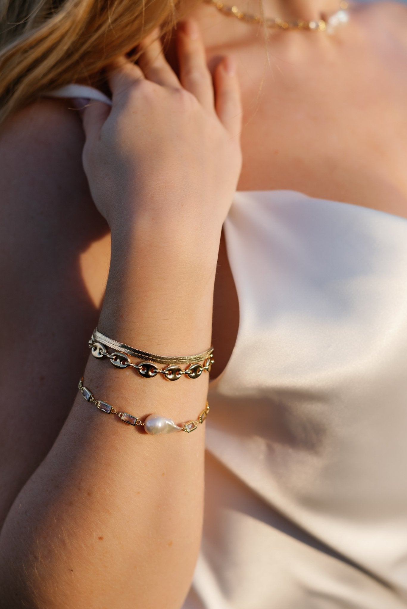 Stacked elegance with several styled gold-filled bracelets from simple herringbone to statement crystal link freshwater baroque pearl bracelet. 