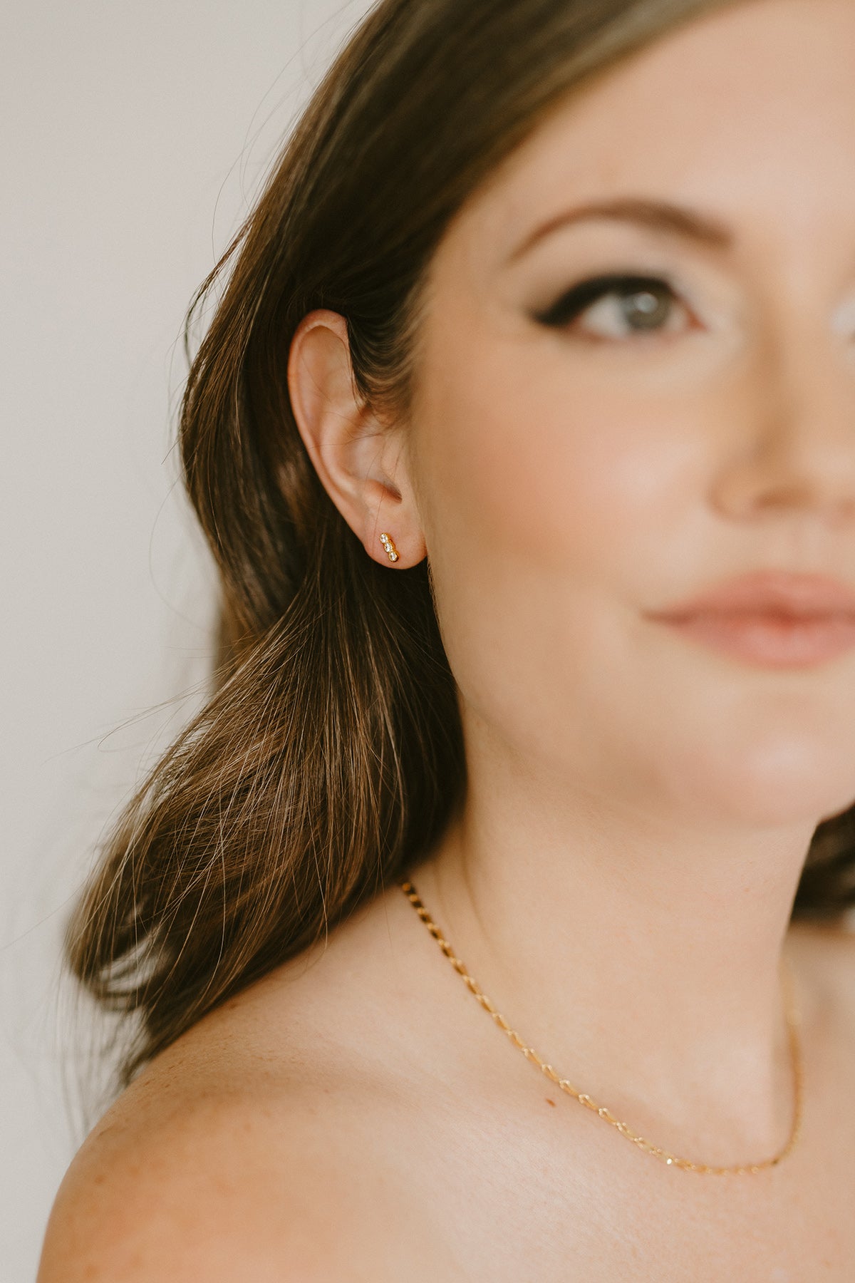 Close-up of a woman wearing a gold-filled earring with 3 crystals and gold necklace. Canadian jewelry brands. Canadian jewelry designer. Everyday jewelry.