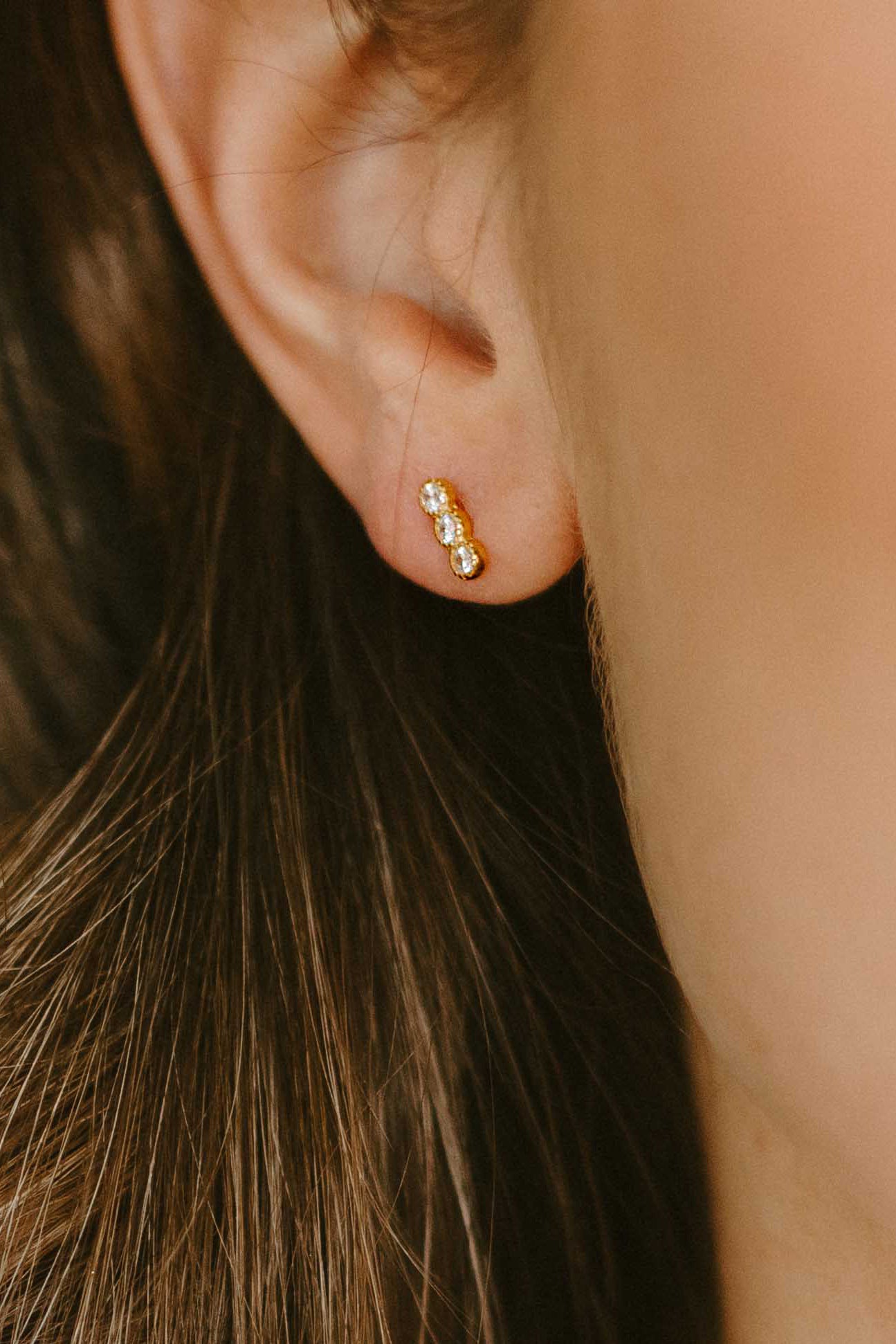 Close-up of an ear wearing a gold-filled earring with 3 cubic zirconia crystals. Everyday jewelry. Affordable jewelry. Handmade Canadian jewelry. 