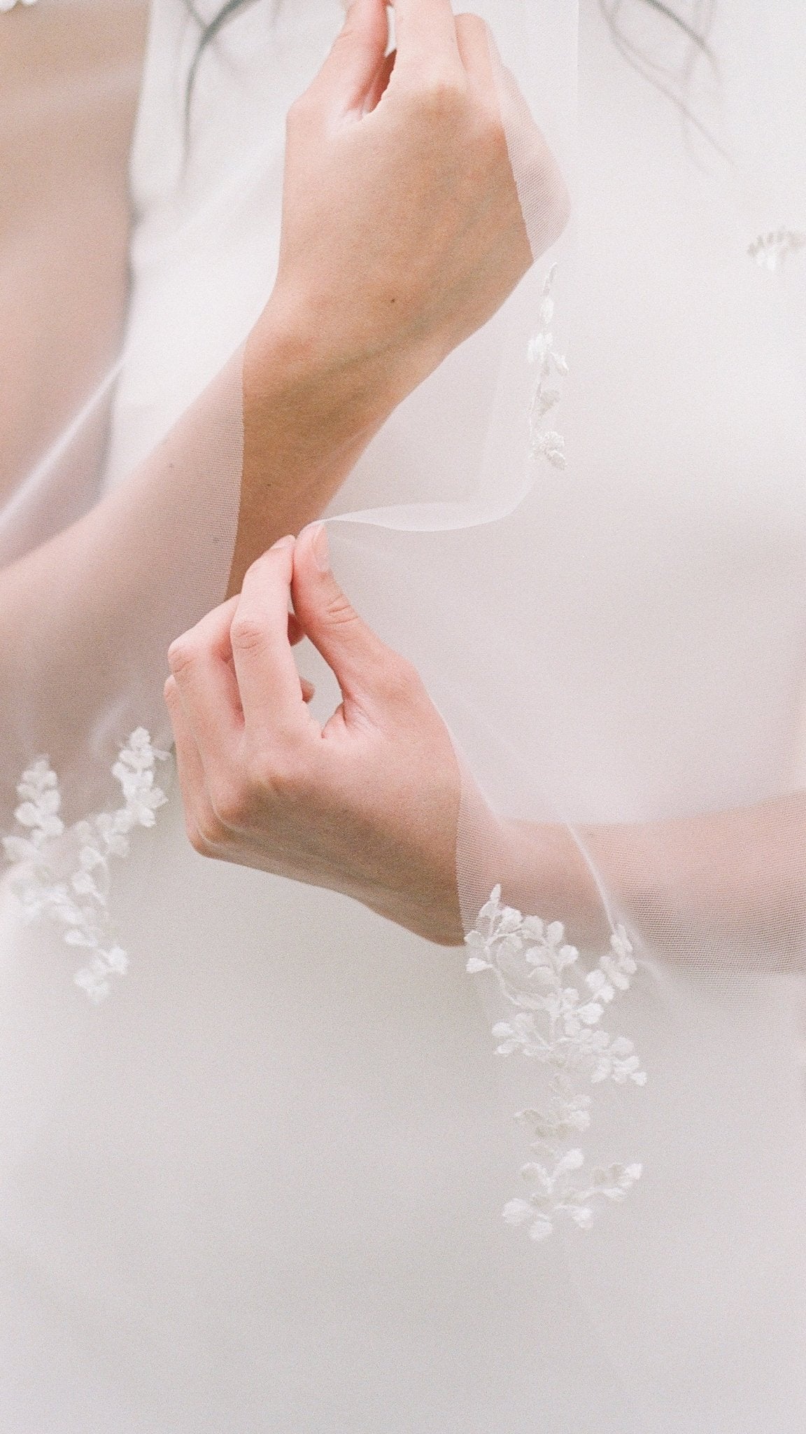 Bride holds the edges of the Wisteria Wedding Veil to show off the leafy lace trim. Canadian weddings. Wedding Canada. Wedding veils Canada. Bridal Hair Accessories. Bridal Accessories. Canadian Bridal Accessories. Handmade Canadian Accessories. Canadian handmade Accessories. Canadian designer. Canadian artist.