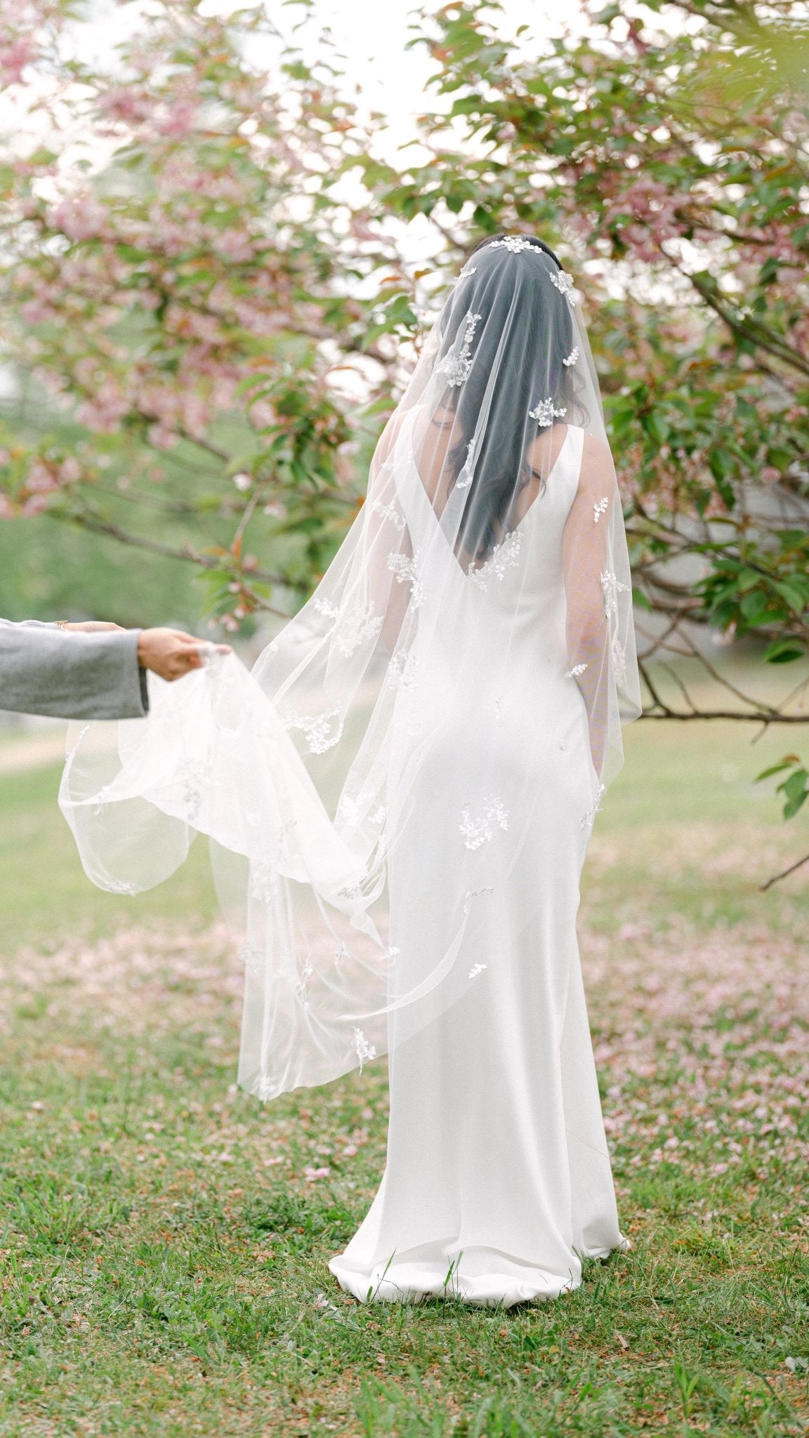 A bride walks on while someone out of shot holds up the bottom of her Wisteria Lace Leaf Wedding Veil. Canadian weddings. Wedding Canada. Wedding veils Canada. Bridal Hair Accessories. Bridal Accessories. Canadian Bridal Accessories. Handmade Canadian Accessories. Canadian handmade Accessories. Canadian designer. Canadian artist.