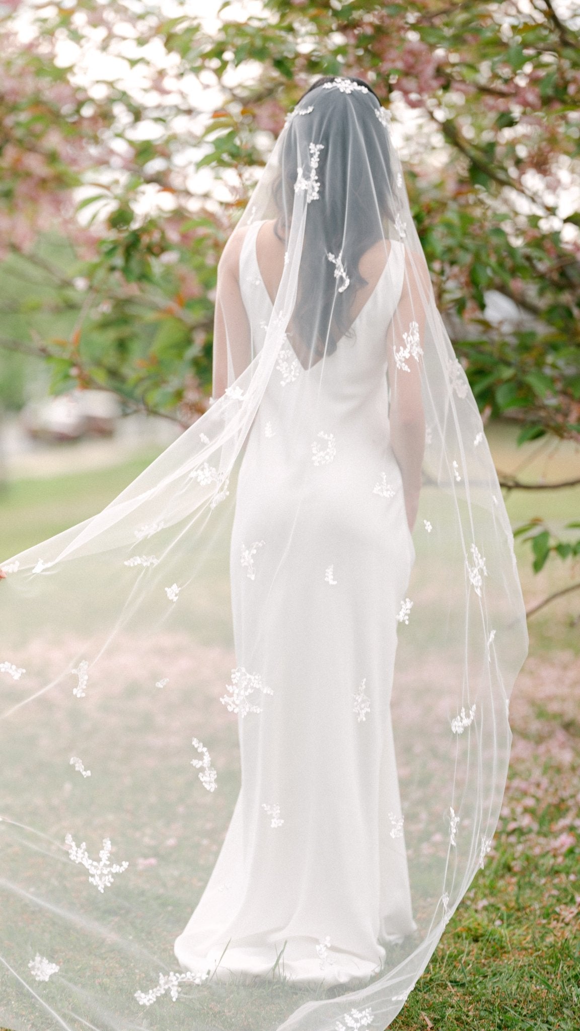 A bride stands amongst greenery whilst her Wisteria Lace Leaf Wedding Veil is held up and spread out. Canadian weddings. Wedding Canada. Wedding veils Canada. Bridal Hair Accessories. Bridal Accessories. Canadian Bridal Accessories. Handmade Canadian Accessories. Canadian handmade Accessories. Canadian designer. Canadian artist.